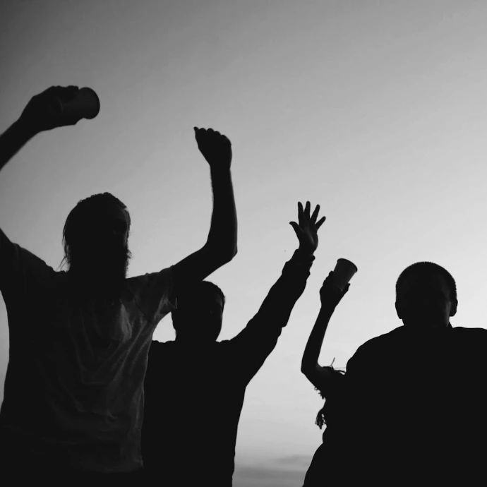 Silhouettes of people celebrating against a purple sky